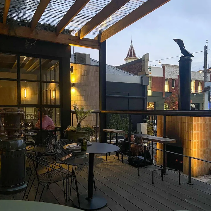 The Arborist rooftop terrace at dusk with brick fireplace and Geelong streetscape behind