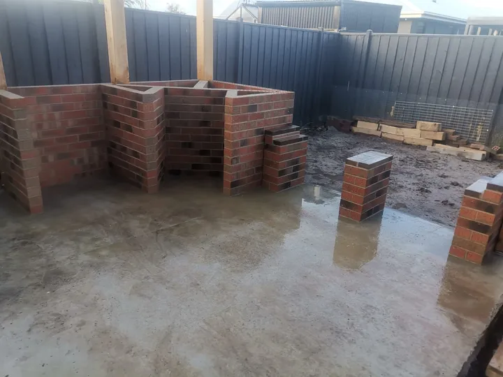 Face-brick outdoor BBQ structure and piers under construction on a new concrete slab