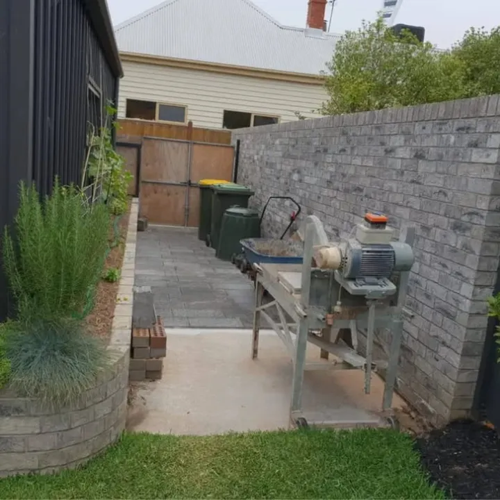 Grey-brick courtyard boundary wall with a curved brick planter and paved courtyard