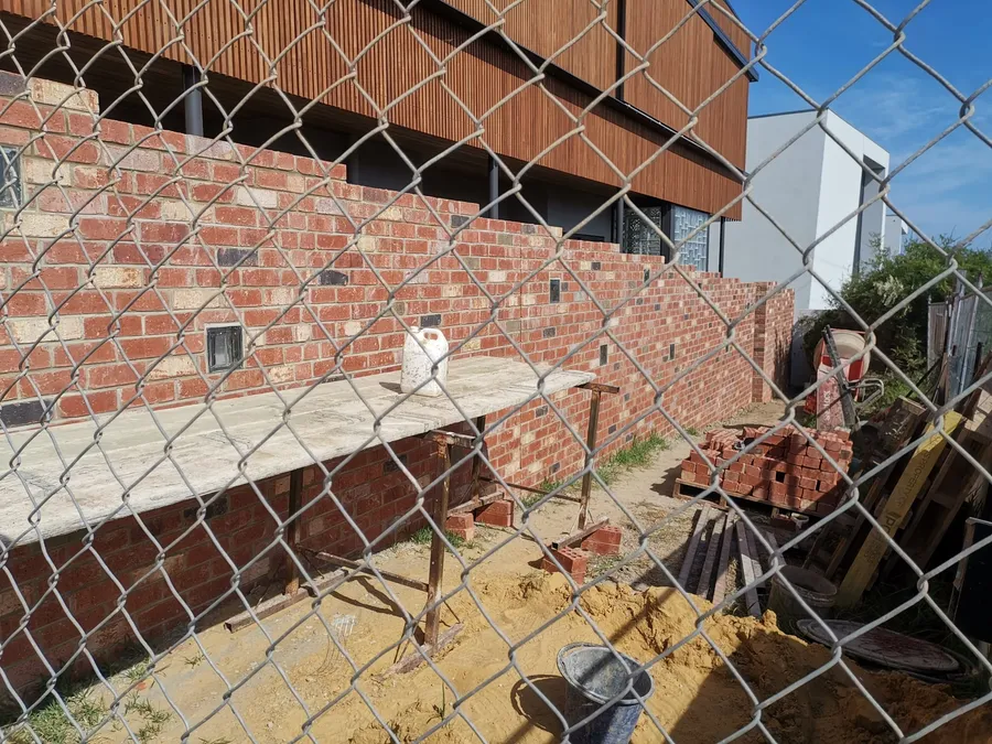 Stepped recycled-brick feature wall with stepped coursing against a modern timber-clad home in Geelong