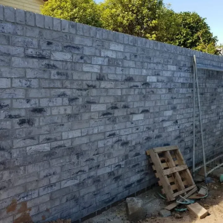 Long grey-brick boundary wall with a neat weathered finish along a property line